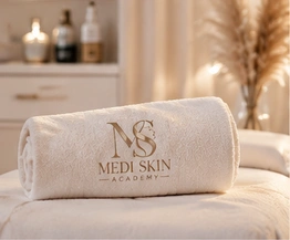 Ivory towel embroidered with the Medi Skin Academy logo in a marble treatment room